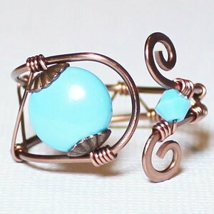 May include: A copper wire ring with a light blue gemstone and a smaller light blue crystal accent.