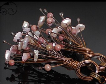 May include: A pair of earrings with a copper wire base and pink and white gemstone accents. The earrings are made with a cluster of small stones and a larger stone at the bottom.