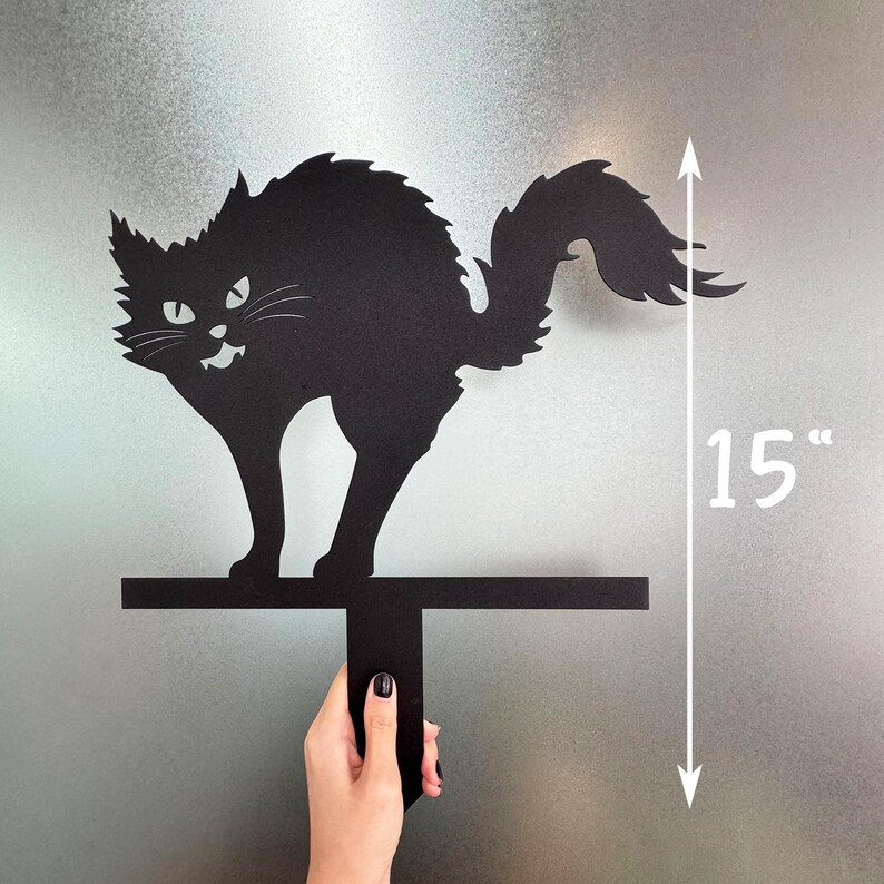 May include: Black metal cat silhouette with an arched back and a menacing expression. The cat is 15 inches tall and mounted on a horizontal bar with a vertical handle. A Halloween-themed decoration.