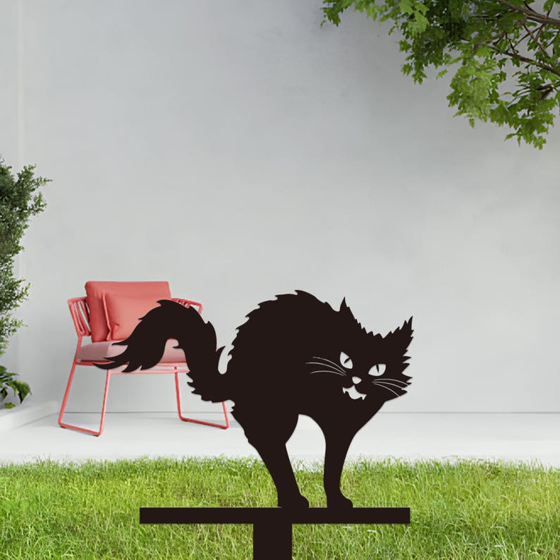 May include: A black metal cat silhouette with an arched back and a snarling expression. The cat is mounted on a horizontal bar, suitable for yard or garden decor. The cat has a fluffy tail and pointed ears.