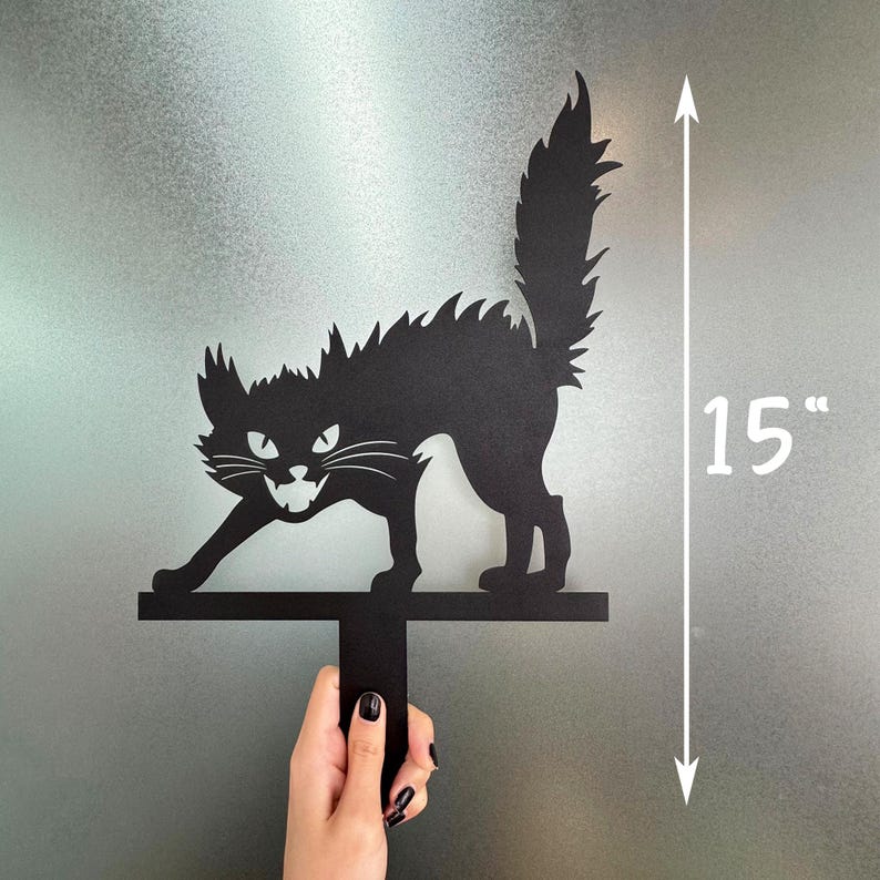 May include: Black metal cat silhouette with a menacing expression, measuring 15 inches in height. The cat is in a Halloween theme, with a spiked back and tail. The cat is held by a black handle.