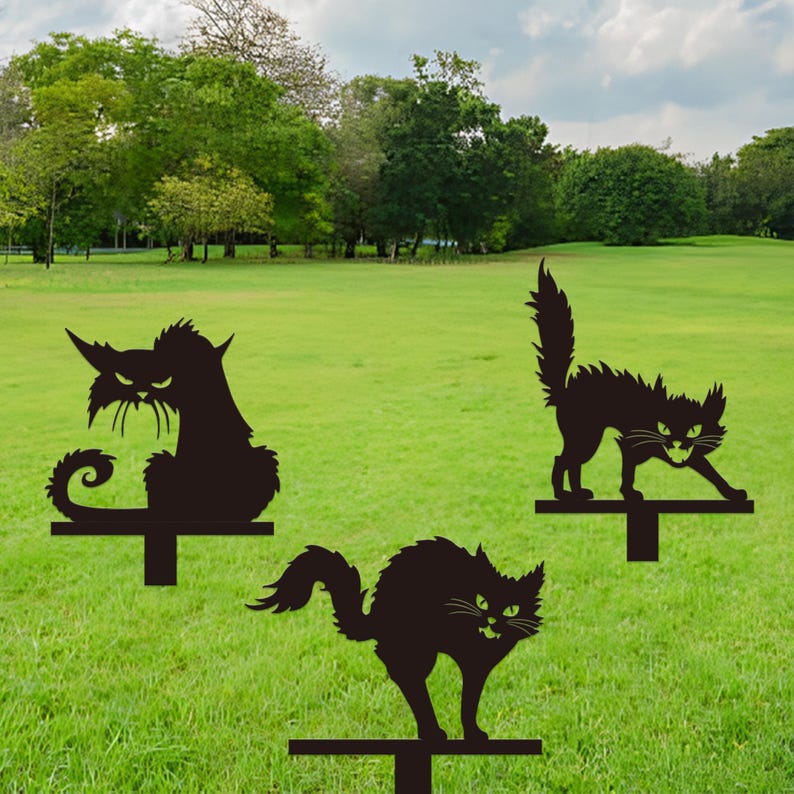May include: Three black metal cat yard stakes with menacing expressions. Each cat has a unique pose, with one sitting, one crouching, and one standing. The stakes are designed to be placed in a lawn or garden.