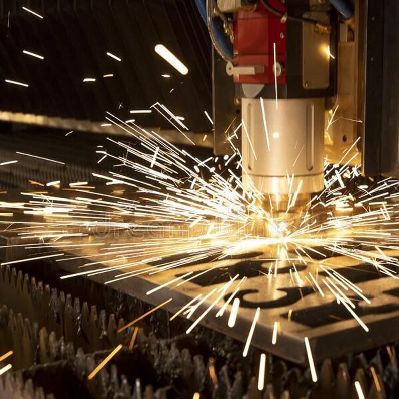 May include: A close-up of a laser cutter in operation, creating sparks as it cuts through a metal sheet. The machine is red and silver, with a focused beam of light. The metal sheet is dark, with cut-out shapes.
