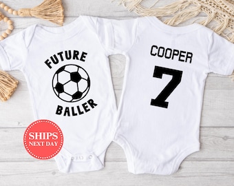 May include: Two white baby onesies. One onesie has a soccer ball graphic and the text "FUTURE BALLER". The other onesie has the text "COOPER 7" on the back.