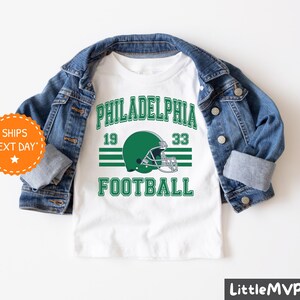 a white shirt with a green football helmet on it