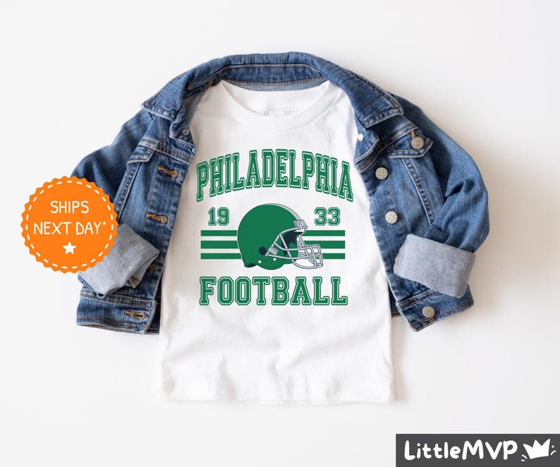 a white shirt with a green football helmet on it