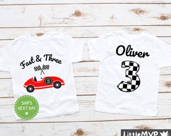 May include: Two white t-shirts with a racing car theme. One shirt has a red race car with the text "Fast & Three" and the other shirt has a black and white checkered number "3" with the name "Oliver" above it.