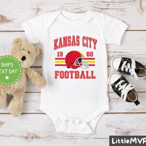 a teddy bear sitting next to a kansas city football shirt