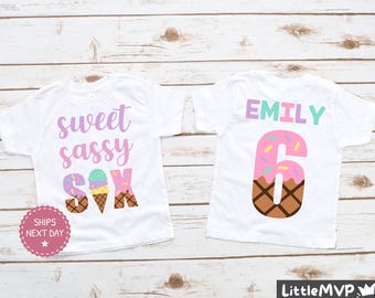 May include: Two white t-shirts with ice cream cone designs. One shirt says "sweet sassy six" and the other says "Emily" with the number six in an ice cream cone.