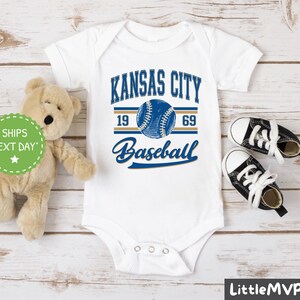 a teddy bear sitting next to a kansas city baseball shirt