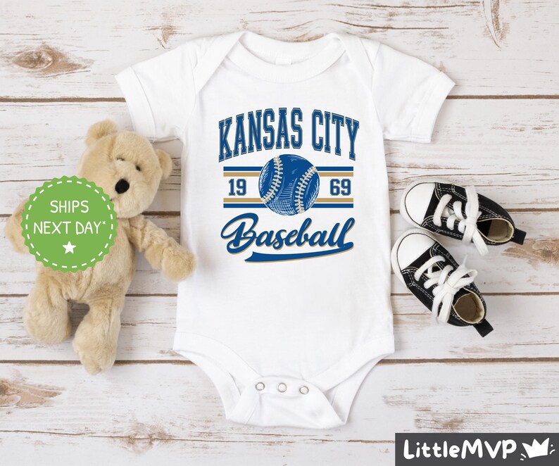 a teddy bear sitting next to a kansas city baseball shirt