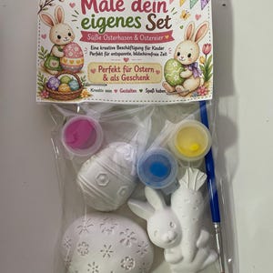Puede incluir: Un kit de manualidades de Pascua con pintura, un pincel y figuras de Pascua de cer&aacute;mica. El kit incluye un conejito, una zanahoria y huevos. El embalaje tiene texto en alem&aacute;n e ilustraciones de conejos y huevos.