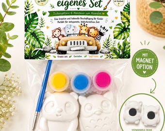 Puede incluir: Un kit de manualidades en una bolsa de plástico transparente con una tarjeta superior que muestra animales de la selva y el texto Male dein eigenes Set. Incluye un pincel azul, tres botes de pintura en amarillo, azul y rosa, y dos figuras de cerámica.