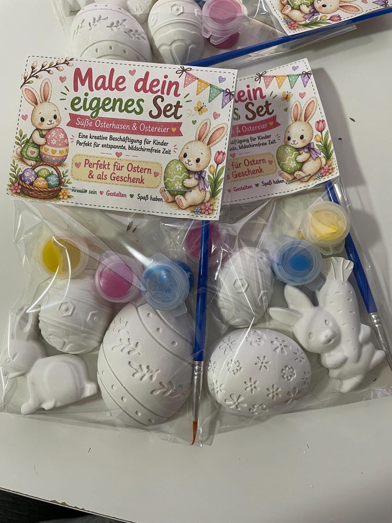 Puede incluir: Juego de pintura de Pascua para pintar. El juego incluye huevos de Pascua y figuras de conejos de cer&aacute;mica blanca, botes de pintura y pinceles. El embalaje presenta ilustraciones de conejos y huevos, con texto en alem&aacute;n.