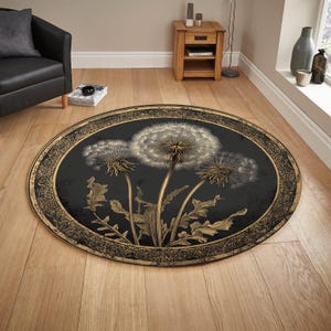 Op de afbeelding: Een ronde vloerkleed met een paardenbloemmotief. Het kleed heeft een zwarte achtergrond met een goudkleurige ovale rand. De paardenbloemafbeelding is in goud- en wittinten, met gedetailleerde zaadkoppen en stelen. Het kleed ligt op een houten vloer.