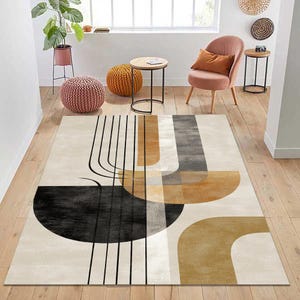 Può includere: Un tappeto rettangolare con un design astratto. Il tappeto presenta uno sfondo color crema con forme geometriche nere, marroni e grigie. Linee nere verticali e forme curve completano il design. Il tappeto è posato su un pavimento in legno.
