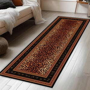 May include: A rectangular runner rug with a leopard print design. The rug features a central leopard print pattern in shades of brown and tan, framed by a black border with a decorative pattern and a thin red border.