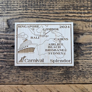 May include: A wooden plaque with a map of an itinerary for a cruise on the Carnival Splendor. The map shows stops in Singapore, Lombok, Bali, Cairns, Airlie Beach, Brisbane, and Sydney. The text on the plaque reads "Singapore Lombok 2024" and "Carnival Splendor".