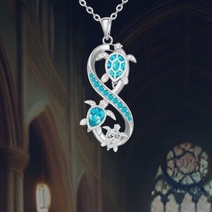 May include: Silver infinity necklace with three turquoise sea turtle charms. The turtles are adorned with sparkling blue crystals.