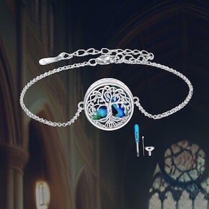 May include: Silver chain bracelet with a round pendant featuring a tree of life design. The pendant has a blue and green abalone shell inlay. The bracelet comes with a small funnel and a screwdriver.