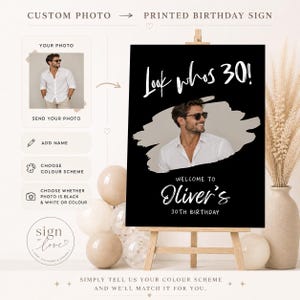 May include: A custom birthday sign on an easel featuring a black background with white text that reads Look whos 30! and Welcome to Oliver's 30th Birthday. The sign includes a central photo of a person wearing a white shirt and sunglasses.