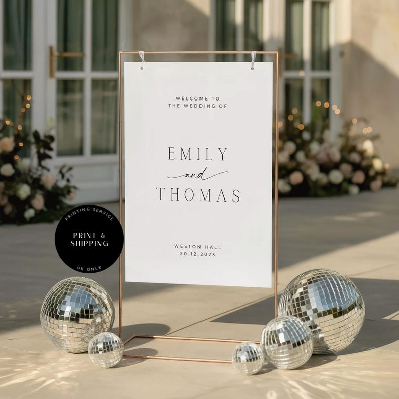May include: A wedding welcome sign with a copper frame displays the names "Emily and Thomas" and event details. The sign is accompanied by disco balls of varying sizes. The text reads "Welcome to the wedding of" and "Weston Hall 20.12.2023".