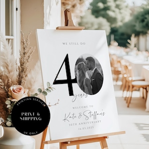 May include: A white sign with black text and a black and white photo of a couple. The sign reads "We still do 40 years. Welcome to Kate & Steffan's 30th Anniversary 16.03.2025".
