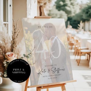 May include: A white sign with a photo of a couple celebrating their 40th anniversary. The sign says "We still do" and "Welcome to Kate & Steffan's 40th Anniversary 16.03.2025".