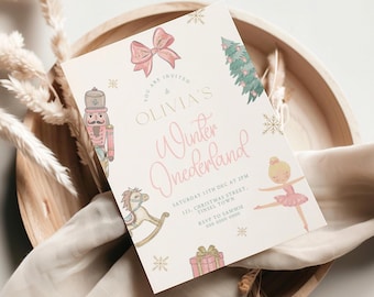 以下が含まれることがあります： 「OLIVIA'S Winter Onederland」の文字が入った薄いピンク色の招待状。くるみ割り人形、木馬、バレリーナ、プレゼント、リボン、クリスマスツリー、雪の結晶のイラストが描かれています。招待状は木製のトレイに置かれています。
