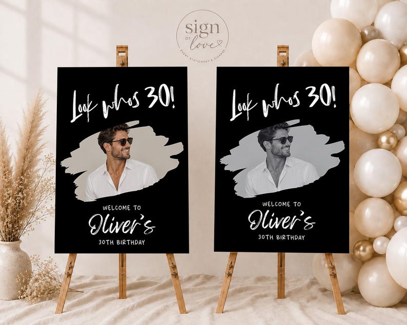 May include: Two identical black rectangular birthday signs on wooden easels. Each sign features the white text Look whos 30!, a central grayscale photo of a person wearing sunglasses and a white shirt, and the text Welcome to Oliver's 30th Birthday.
