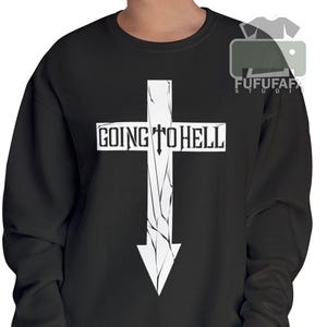 May include: Black sweatshirt featuring a white cross graphic with the text "GOING TO HELL". The cross design has a cracked, distressed appearance. The sweatshirt is a solid black color.