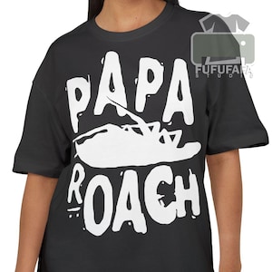 May include: Black t-shirt with a white graphic that reads "PAPA ROACH" with a stylized cockroach illustration in the center. The shirt is a casual, short-sleeved style.