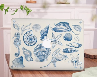 May include: A white laptop with a blue and white seashell design. The design features a variety of seashells, starfish, a crab, a stingray, and a seahorse.