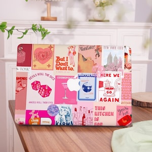 May include: A laptop case featuring a collage of retro-style images in pink, red, and white. The design includes text like "Devils Roll the Dice" and "You're Hot", along with illustrations of dice, cocktails, and a cat.