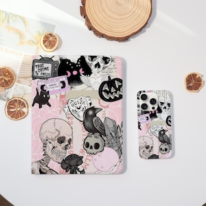 May include: A pink tablet case and phone case with a spooky Halloween theme. The cases feature skulls, ravens, pumpkins, and the text "True Crime & Chills". The designs are in black and white with pink accents.