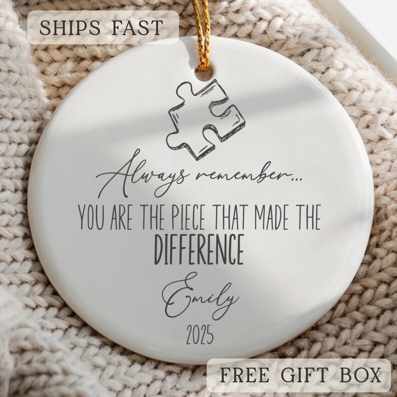 May include: Round white ceramic ornament with a gold hanging string. The ornament has a puzzle piece design and the text "Always remember... YOU ARE THE PIECE THAT MADE THE DIFFERENCE Emily 2025".