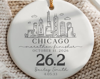 May include: A round white ceramic ornament featuring a black line art illustration of the Chicago skyline. Text reads: CHICAGO, marathon finisher, OCTOBER 11, 2026, 26.2, Bailey Smith, and 4:05:33. The ornament hangs from a gold-colored string.