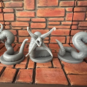 May include: Three gray, plastic, miniature alien creatures with tentacles and segmented bodies. The creatures are posed on circular bases.