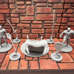 May include: A collection of gray miniature fantasy game pieces, including two armored figures, a shield, a large insect-like creature, and various weapons. The pieces are set against a brick wall backdrop.
