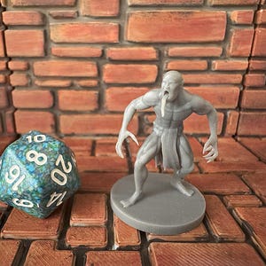 May include: A gray painted miniature figurine of a humanoid creature with a long tongue, standing on a gray base. The figurine is posed with its arms outstretched and its head tilted back. The figurine is standing on a brick surface.