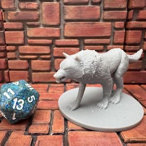 May include: A gray wolf figurine stands on a gray circular base, with a detailed fur texture. A multi-sided die with blue and green patterns is next to the wolf. The background is a brick wall.