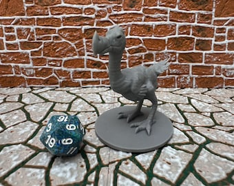 May include: A gray 3D-printed dodo bird figurine stands on a gray circular base, with a blue and green polyhedral die next to it. The dodo has a large beak and is posed as if walking. The background features a brick wall and a stone-like surface.