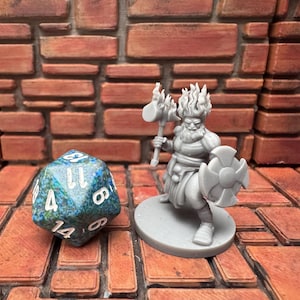 May include: A grey miniature figure of a bearded warrior with a hammer and shield, standing on a circular base. Beside it is a multi-sided die with blue and green patterns and white numbers. The background is a brick-like surface.