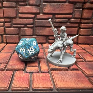 May include: A blue and green marbled D20 die with white numbers next to a grey miniature of a figure riding a mechanical beast. The background is a brick wall and a brick-patterned surface.