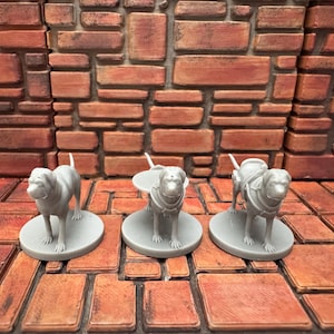 May include: Three gray miniature dog figurines, each standing on a circular base. One dog stands alone, while the other two wear armor and saddlebags. The background features a brick wall and floor.