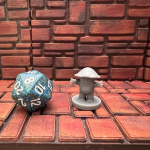 May include: A blue and green twenty-sided die and a gray mushroom-shaped figurine with outstretched arms stand on a brick-patterned surface. The figurine is on a circular base. The background is a brick wall.
