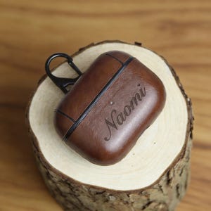 Peut inclure: Une tasse en c&eacute;ramique blanche avec une anse noire et l'inscription "But First, Coffee" en gras noir. La tasse est pos&eacute;e sur un fond flou, sugg&eacute;rant un cadre chaleureux.