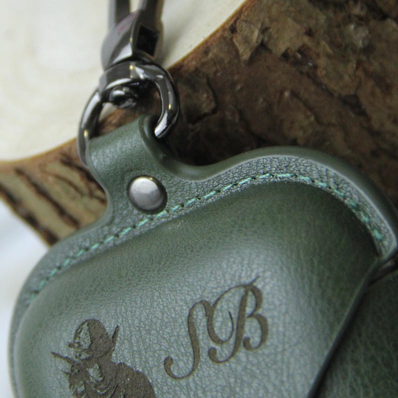 Op de afbeelding: Groene leren etui met een zilverkleurige sluiting. De etui heeft een reli&euml;f ontwerp van een conquistador en de initialen "SB". De stiksels zijn lichtgroen.