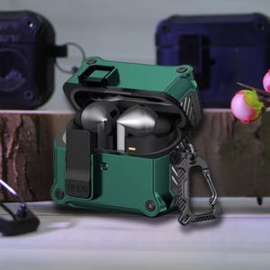 May include: A green protective case for wireless earbuds, open to reveal the earbuds inside. The case has a rugged design with a carabiner clip and the word "OPEN" visible. Other cases are in the background.