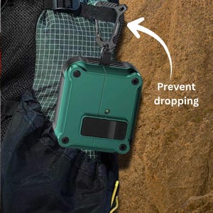 May include: A green protective case for wireless earbuds, secured to a backpack with a black carabiner clip. The case is rectangular with rounded corners and a black opening. The text "Prevent dropping" is visible.